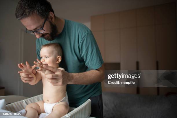 vater kümmert sich um seinen kleinen jungen - changing diaper stock-fotos und bilder