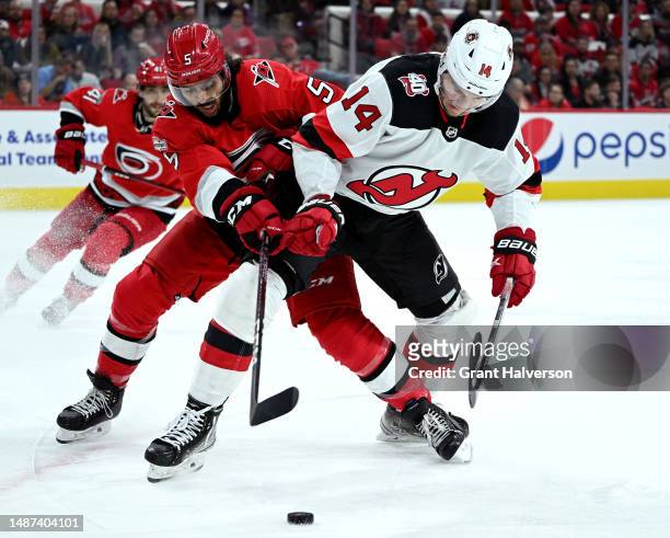 Jalen Chatfield of the Carolina Hurricanes battles Nathan Bastian of the New Jersey Devils for the puck during the third period in Game One of the...