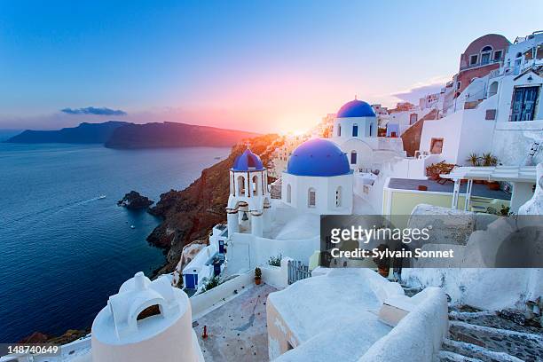 blue domed churches at sunset, oia, santorini - grekiska övärlden bildbanksfoton och bilder