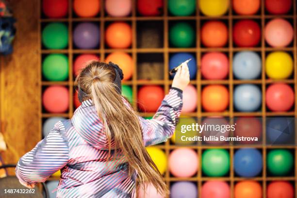 female child shooting at goal while playing balloon darts in amusement park - throwing darts stock pictures, royalty-free photos & images