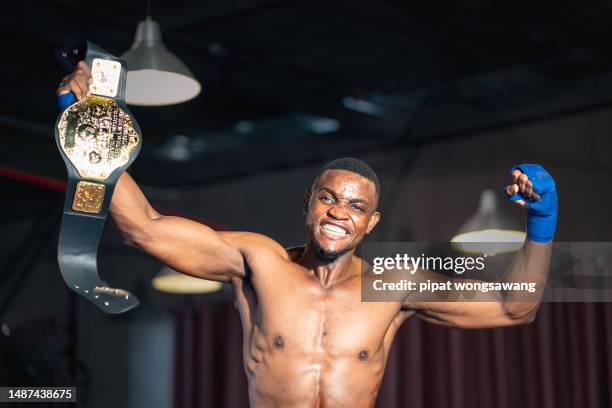 the winning boxer is raising his hands in joy with the championship belt. - championship belt stock pictures, royalty-free photos & images