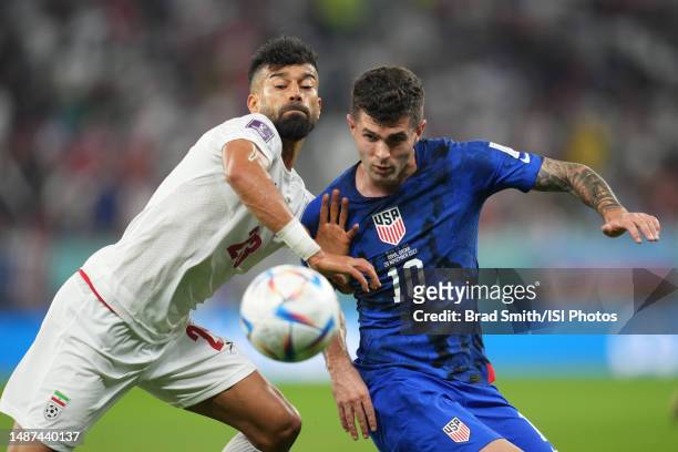 Ramin Rezaeian ofIR Iran battles for the ball with Christian Pulisic of the United States during a FIFA World Cup Qatar 2022 Group B match between IR...