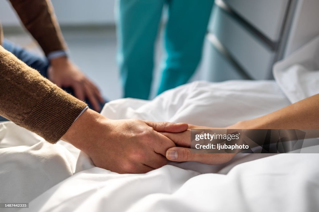 Paciente sosteniendo la mano de su marido en el hospital.