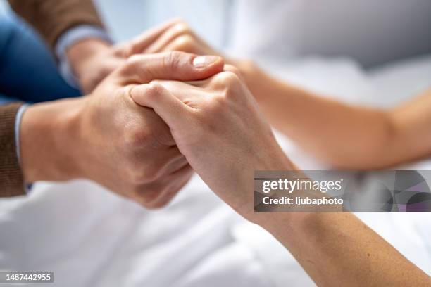 man holding woman hand in hospital bed. - care home bed stock pictures, royalty-free photos & images