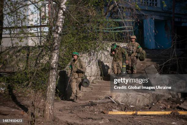 Ukrainian military with Kalashnikov rifles and Javelin launcher walk at residential district on April 17, 2023 in Bakhmut, Ukraine. In Bakhmut, both...
