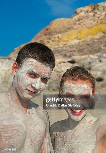 mud-covered young couple bathing at the therapeutic volcanic thermal mud pool, levante beach. - isole eolie stock pictures, royalty-free photos & images