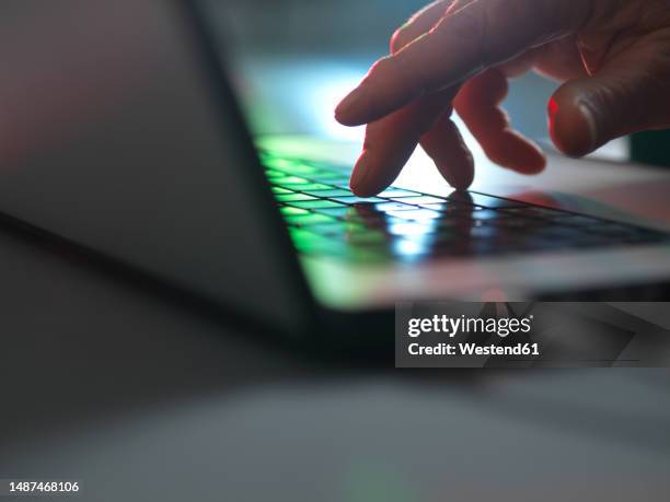 hands touching laptop keyboard in dark at home office - threats stockfoto's en -beelden