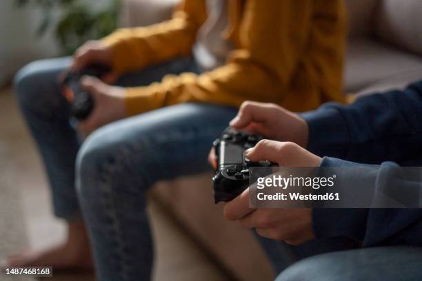 hands of boys holding gaming consoles at home - console stock-fotos und bilder