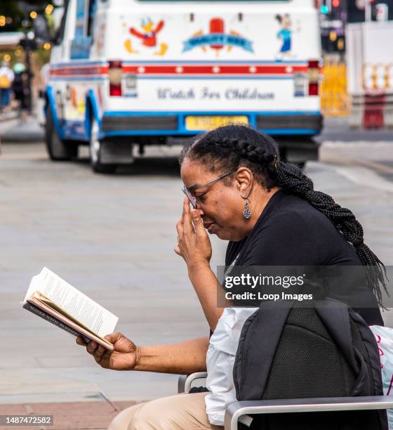 Lady reads a book on a bench in Kings Cross in London.