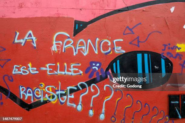 Street wall covered with street art and graffiti in Paris, France. 'Are the French racist ?'.