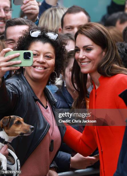 Catherine, Princess of Wales smiles and takes pictures with well wishers during visit the Dog & Duck Pub to speak to members of staff to hear how...