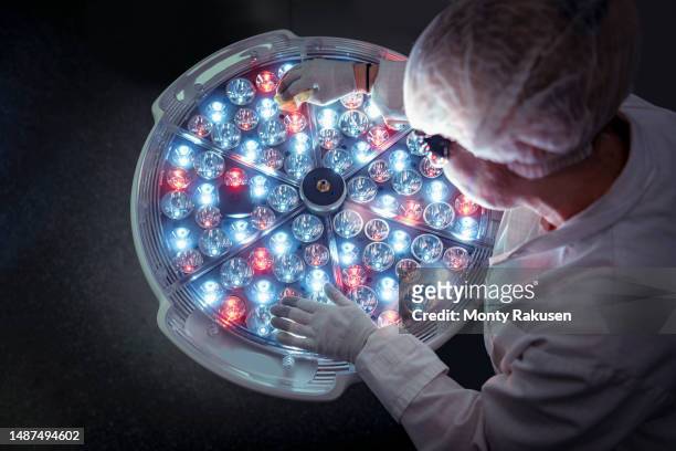 female engineer preparing operating theatre light in factory clean room - biomedical engineering photos et images de collection