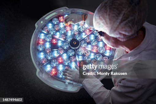 Female engineer preparing operating theatre light in factory clean room Female engineer preparing operating theatre light in factory clean room