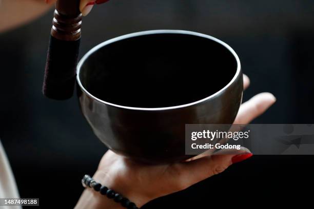 Tibetan singing bowl, buddhist instrument used in sound therapy, meditation and yoga. Bowl in the hands of prayer. Vietnam.