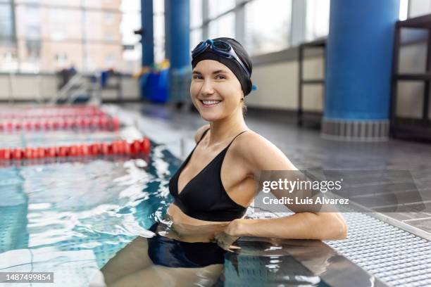 beautiful young woman in swimwear standing in a swimming pool - sleeveless stock pictures, royalty-free photos & images