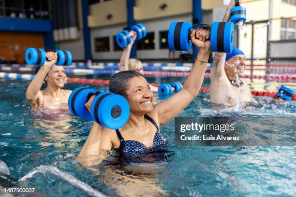 multiracial group of senior people with aqua dumbbells exercising in the swimming pool - hydrotherapy stock pictures, royalty-free photos & images