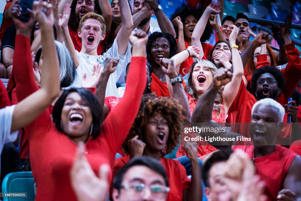 Enthusiastic audience raise their arms up to cheer in celebration of their home soccer team