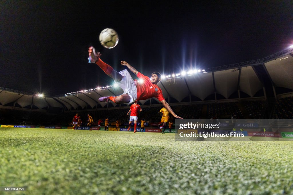 Wide shot photo of male athlete impressively bicycle kicking a soccer ball while in mid-air