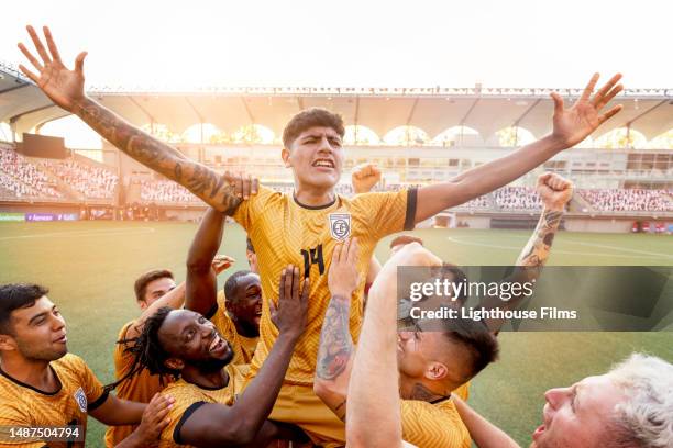 overjoyed team of male athletes raise up their star player after winning a competitive soccer match - international team soccer bildbanksfoton och bilder
