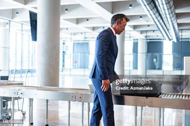 hombre de negocios adulto en el control de seguridad del aeropuerto esperando el control de rayos x de su equipaje - security check fotografías e imágenes de stock