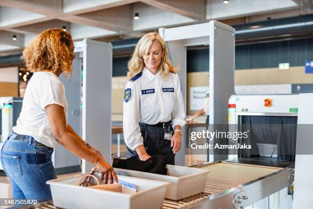 hispanic female passenger pushing a tray to x-ray luggage scanning - airport slovenia stockfoto's en -beelden