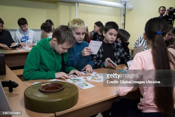 Children use game cards to learn types of dangerous, and how to behave in case of their detection during a mine safety lesson conducted by the State...