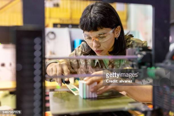 young woman using a 3d printer machine to print a prototype - 3d printers stock pictures, royalty-free photos & images