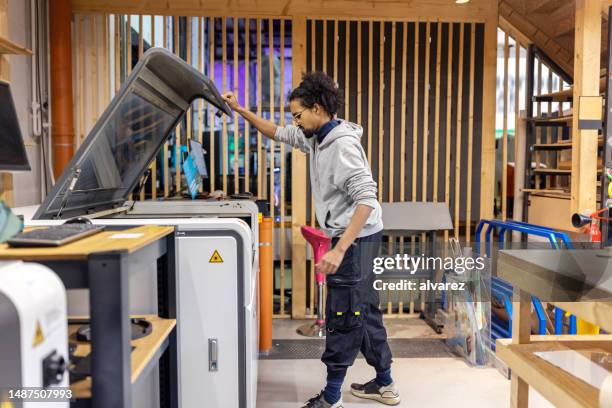 junger mann, der mit industriellem laserschneider im maker-space arbeitet - holz laser stock-fotos und bilder