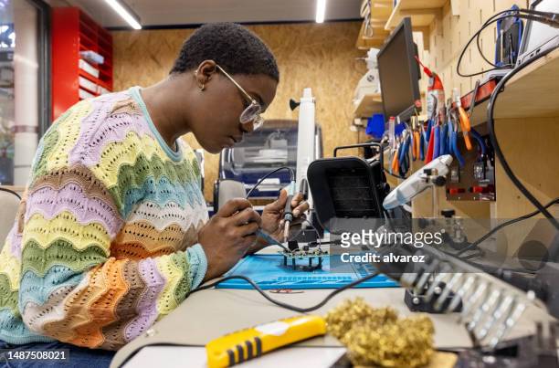 afrikanische frau repariert leiterplatte im maker-raum - elektrischer widerstand stock-fotos und bilder