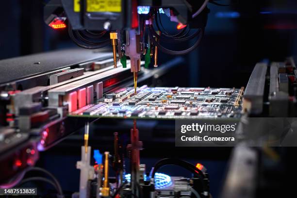robotic arm installing component at circuit board - semiconductor stockfoto's en -beelden