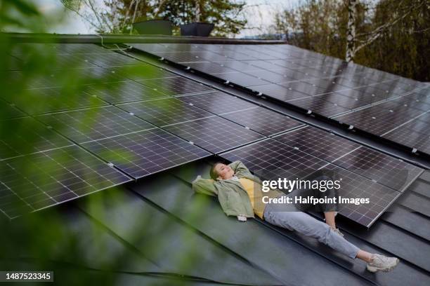 happy woman resting on her rooftop full of solar panels. - energía solar fotografías e imágenes de stock