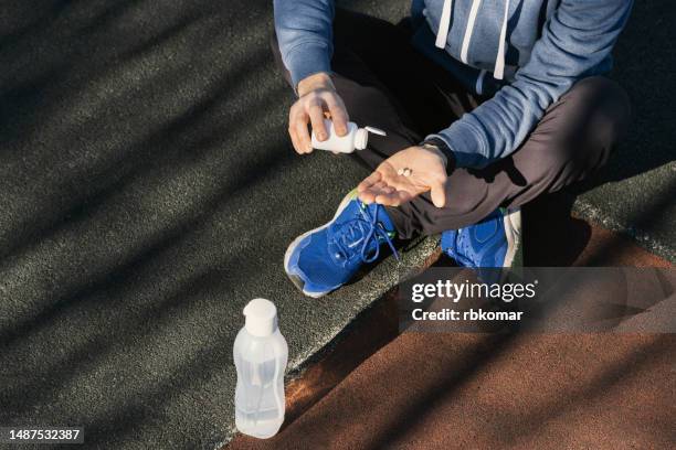 sports nutritional supplements - athlete taking vitamins or pills in training outdoors - doping bildbanksfoton och bilder