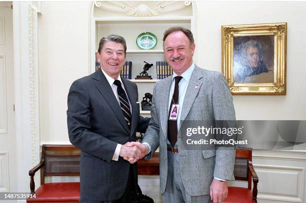 American politician US President Ronald Reagan and actor Gene Hackman shakes hands as they pose for a photo in the White House's Oval Office,...