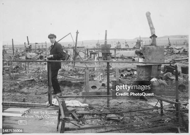 View of an unidentified man as he walks walking through the ruins of the striking miners' tent colony, Ludlow, Colorado, April 20, 1914. The tent...