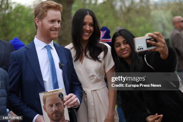 Two impersonators of the Duke and Duchess of Sussex, Harry and Meghan, take photos with people camped out next to Buckingham Palace, May 4 in London,...