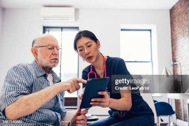 enfermera y su paciente revisando exámenes médicos en una tableta y firmando un acuerdo de privacidad - visita a domicilio fotografías e imágenes de stock