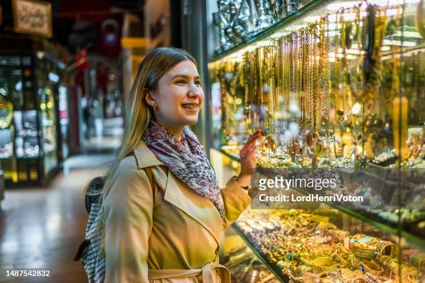 femme regardant la vitrine d’une bijouterie - desire stock photos et images de collection