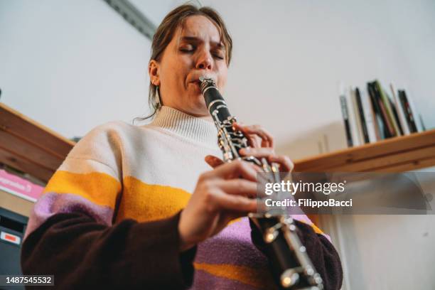 a woman is playing clarinet for practice - klarinet stockfoto's en -beelden