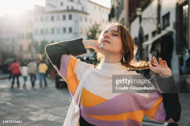 eine frau entspannt sich bei sonnenuntergang in der stadt - milestone stock-fotos und bilder