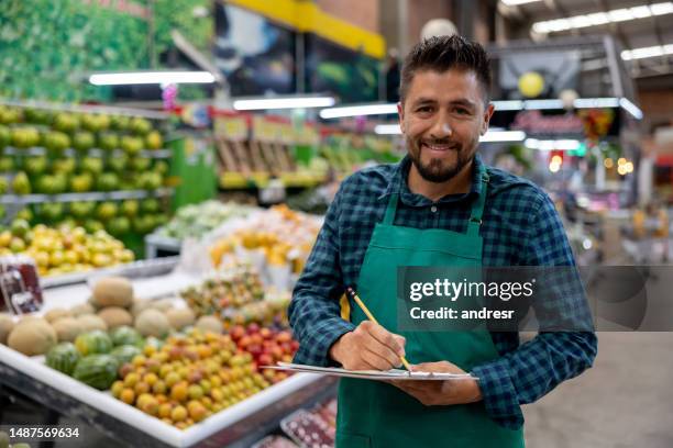glücklicher einzelhandelskaufmann bei der arbeit im supermarkt - gemüseladen stock-fotos und bilder