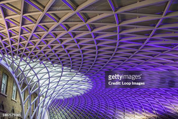 The abstract Kings Cross station ceiling lit up in purple lighting in London.
