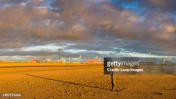 The setting sun over the Irish Sea creates a long shadow behind one of the Iron Men at Another Place on Crosby Beach.