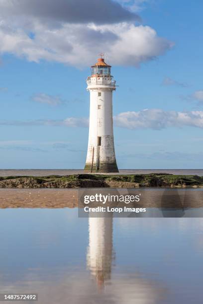 New Brighton Lighthouse reflects in a pool of water as the tide goes out.