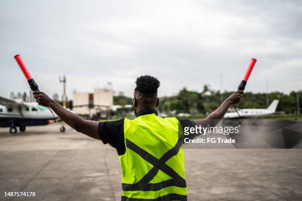 man signaling the pilot with marshalling wands on airport - airport worker stock pictures, royalty-free photos & images