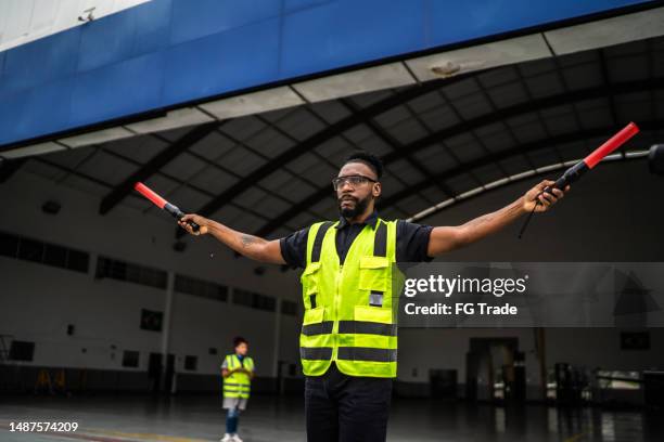 hombre señalando al piloto con varitas de clasificación en el aeropuerto - reflector objeto fabricado fotografías e imágenes de stock