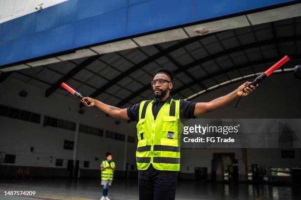 man signaling the pilot with marshalling wands on airport - reflector stockfoto's en -beelden