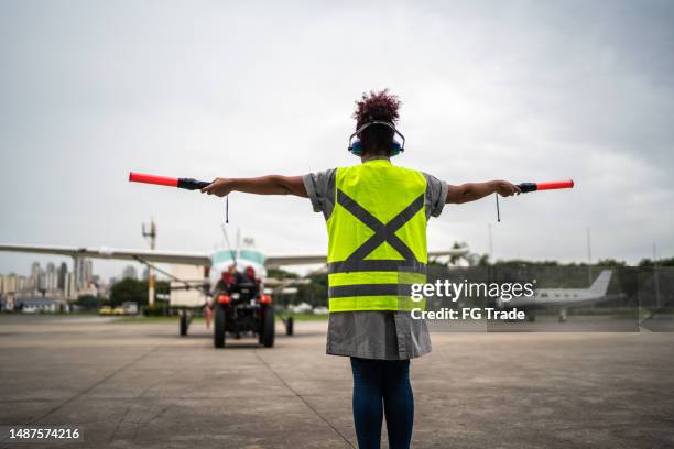 femme signalant le pilote avec des baguettes de triage à l’aéroport - aircraft marshaller photos et images de collection