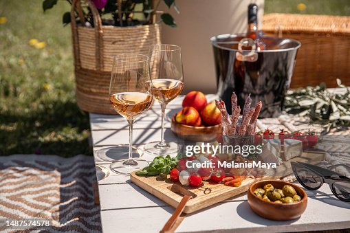 Verres à vin rose avec antipasti pique-collations sur table de fête de jardin ensoleillée Verres à vin rose avec antipasti pique-collations sur table de fête de jardin ensoleillée
