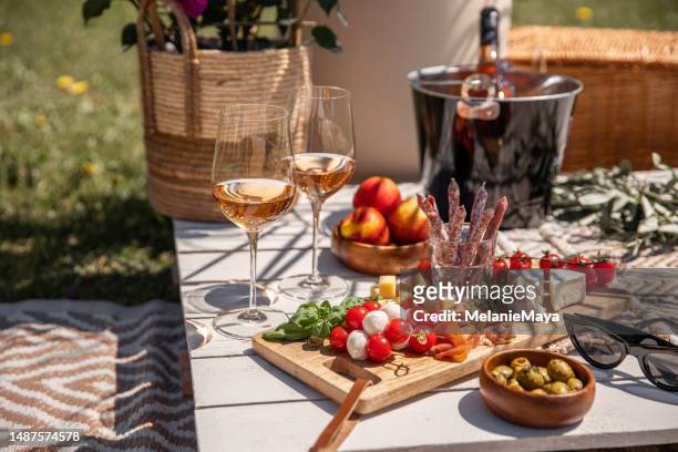 rose wine glasses with antipasti picnic food snacks on sunny garden party table - lunch cheese imagens e fotografias de stock