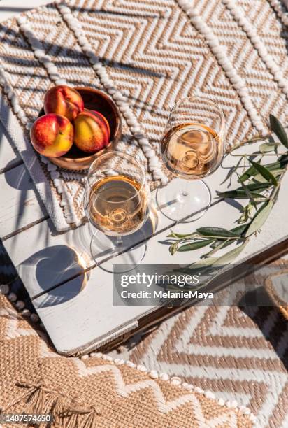 drinking rose wine glasses on white wood table with peaches on sunny mediterranean day - picknick stockfoto's en -beelden